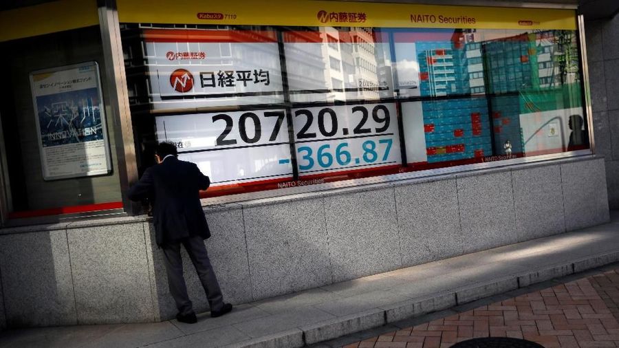 A man paues in front of an electric screen showing Japan's Nikkei share average outside a brokerage in Tokyo, Japan, August 5, 2019.   REUTERS/Issei Kato