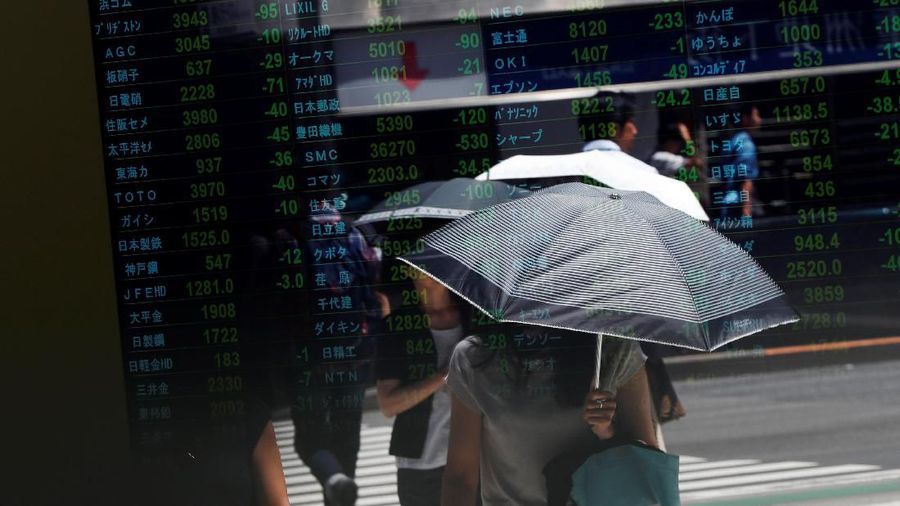 Passersby are reflected on an electronic board showing the exchange rates between the Japanese yen and the U.S. dollar, the yen against the euro, the yen against the Australian dollar, Dow Jones Industrial Average and other market indices outside a brokerage in Tokyo, Japan, August 6, 2019.   REUTERS/Issei Kato