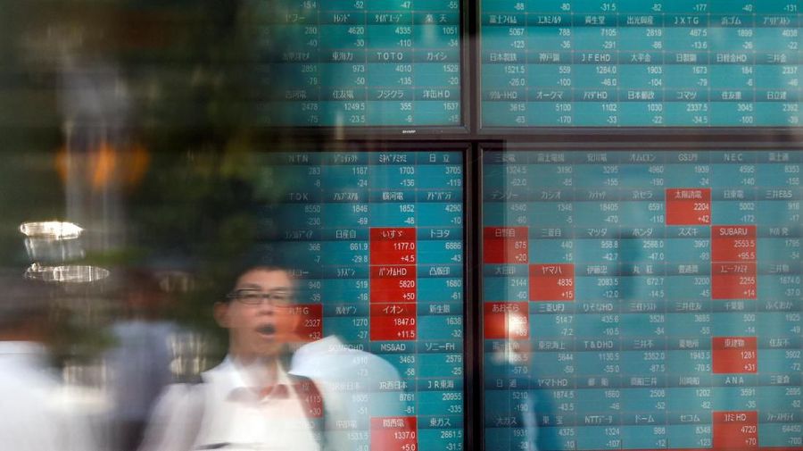 Passersby are reflected on an electronic board showing the exchange rates between the Japanese yen and the U.S. dollar, the yen against the euro, the yen against the Australian dollar, Dow Jones Industrial Average and other market indices outside a brokerage in Tokyo, Japan, August 6, 2019.   REUTERS/Issei Kato