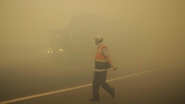 Karena kebakaran hutan, tol Indralaya-Palembang tertutup kabut asap. Petugas sampai harus mengatur lalu lintas saat terjadi kabut asap akibat kebakaran lahan gambut di Desa Pulau Semembu, Indralaya Utara, Ogan Ilir, Sumatra Selatan, Senin (5/8/2019). (ANTARA FOTO/Ahmad Rizki Prabu)