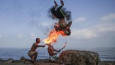 Pria palestina meniupkan api dan menghibur anak-anak yang sedang liburan musim panas di kota Gaza. (Photo by MOHAMMED ABED / AFP)