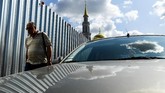 Seorang pria berjalan melewati pagar yang terbuat dari logam yang mengelilingi gedung yang sedang dibangun di dekat Masjid Sobornaya di Moskow, Inggris. (Photo by Kirill KUDRYAVTSEV / AFP)