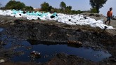 Seorang anak berada di samping tumpukan karung berisi ceceran minyak mentah di Pantai Mekarjaya, Karawang, Jawa Barat, Kamis (8/8/2019). (ANTARA FOTO/Sigid Kurniawan/ama)
