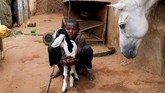 Tajideen, 14, berpose dengan seekor anak kambing, dekat kamar tempat ia biasa tidur dan beristirahat di klub Equestrian di Khartoum. Ia biasa menghabiskan liburan musim panas membantu keluarganya di istal. (REUTERS/Andreea Campeanu)