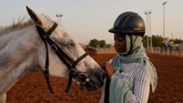 Einas, 18, menyentuh kuda yang ia tengah belajar tunggangi di klub di Khartoum, Sudan. Beberapa perempuan kepada Reuters menuturkan bahwa pada awalnya mereka mendapat tentangan saat akan berkuda, karena perempuan dianggap tidak pantas berpartisipasi di ajang olahraga. (REUTERS/Andreea Campeanu)
