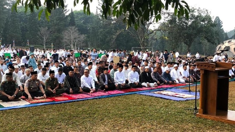 Jokowi menunaikan salat dengan mengenakan baju koko putih, peci hitam dan sarung berwarna gelap.