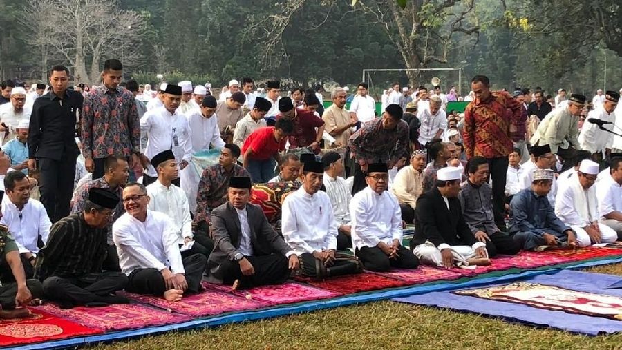 Jokowi menunaikan salat dengan mengenakan baju koko putih, peci hitam dan sarung berwarna gelap.