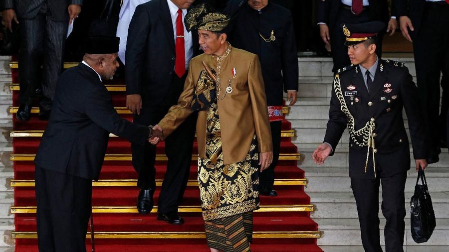 Pakaian adat Sasak yang dikenakan Jokowi berwarna keemasan lengkap dengan tutup kepala dan keris.