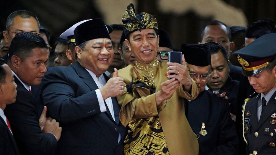 Pakaian adat Sasak yang dikenakan Jokowi berwarna keemasan lengkap dengan tutup kepala dan keris.