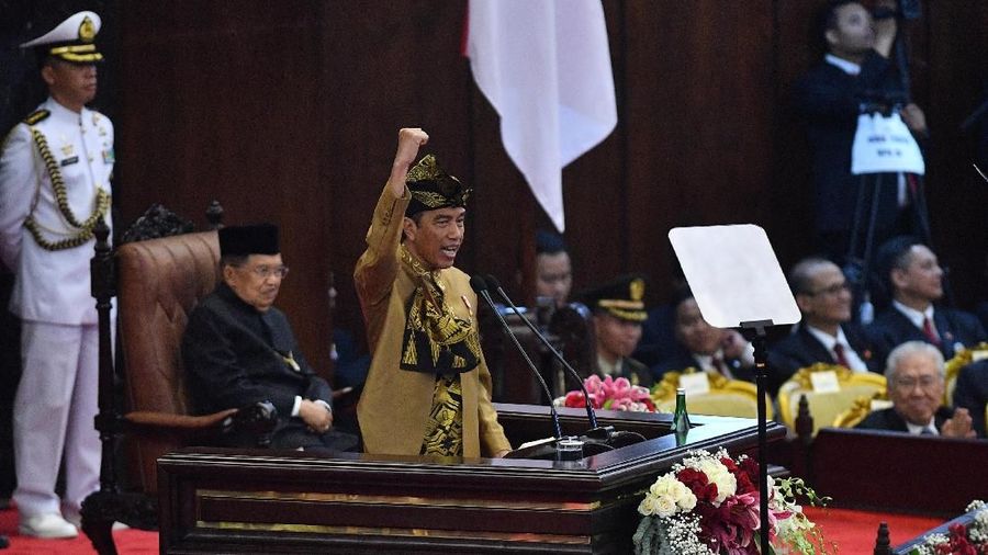 Pakaian adat Sasak yang dikenakan Jokowi berwarna keemasan lengkap dengan tutup kepala dan keris.