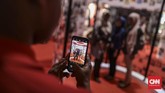 Pengunjung memotret pengunjung lain yang minta diabadikan gambarnya dengan latar ruang pameran Festival Indonesia Maju di Gelora Bung Karno, Jakarta, 22 Agustus 2019. (CNN Indonesia/Bisma Septalisma)
