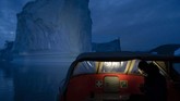 Sebuah kapal mengarungi lautan dan berada di sebelah gunung es di Greenland Timur. Sebelumnya, panas tahun ini turut melelehkan es di wilayah itu. (AP Photo/Felipe Dana)
