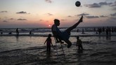 Warga Palestina yang diamputasi, Mohammed Eliwa (17) yang kehilangan kakinya saat bentrokan di perbatasan Israel, tengah bermain bola di pantai. (Photo by MAHMUD HAMS / AFP)