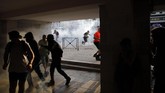 Sejumlah pengunjuk rasa lari menghindari tembakan gas air mata di Bayonne, Prancis. Pemerintah Prancis disebut mengerahkan lebih 13.000 polisi untuk memastikan massa tidak mendekati para pemimpin negara G7 termasuk Presiden AS Donald Trump. (AP Photo/Emilio Morenatti)