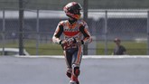 Marc Marquez berjalan setelah sepeda motornya kehabisan bahan bakar. Marquez ke parc ferme diantar steward menggunakan sepeda motor. (Adrian DENNIS / AFP)