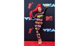 Justina Valentine terlihat seperti banner berjalan dengan jumpsuit panjang dengan aneka tulisan di tubuhnya. (Johannes EISELE / AFP)