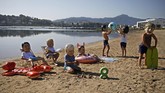 Aktivis Oxfam mengenakan topeng para pemimpin G-7 dan menampilkan pertunjukan di suatu pantai di Hendaye, Perancis. (AP Photo/Emilio Morenatti)
