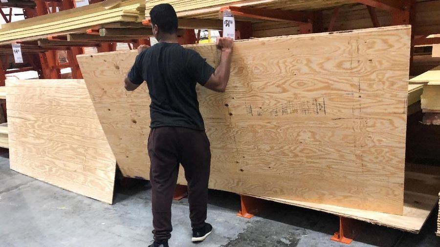 A man lifts a sheet of plywood at a Home Depot store ahead of the arrival of Hurricane Dorian in Miami, Florida, U.S. August 30, 2019.  REUTERS/Marco Bello