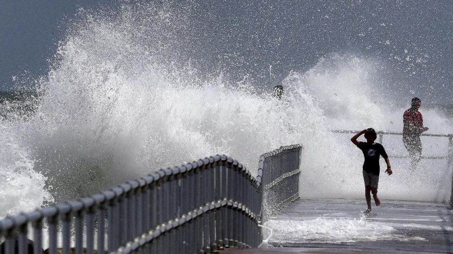 A child runs as a wave generated by Hurricane Dorian crashes into the jetty at Lighthouse Point Park in Ponce Inlet, Fla., Monday, Sept. 2, 2019. (Joe Burbank/Orlando Sentinel via AP)