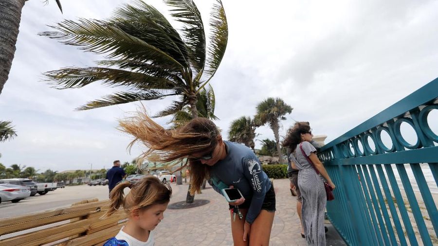 Kristen Davis watches the high surf from a boardwalk overlooking the Atlantic Ocean with her daughter Addie Davis, 4, as winds from Hurricane Dorian blow the fronds of a palm tree in Vero Beach, Fla., Monday, Sept. 2, 2019. (AP Photo/Gerald Herbert)