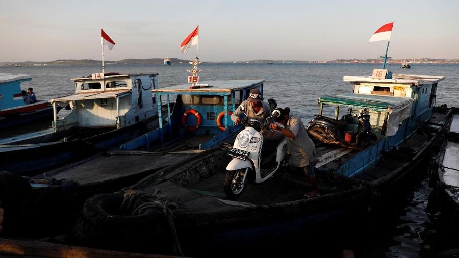 People unload a motorbike from a wooden boat as they arrive from Balikpapan at a port in North Penajam Paser regency, East Kalimantan province, Indonesia, August 28, 2019. Picture taken August 28, 2019. REUTERS/Willy Kurniawan
