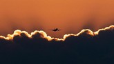 Sebuah pesawat terbang di atas awan menjelang matahari terbit saat mendekati bandara di Frankfurt, Jerman. (AP/Michael Probst)