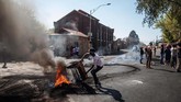 Seorang pria mengangkat perabot yang terbakar selama kerusuhan di pinggiran Turffontein, Johannesburg, (2/9). Saat itu, demonstran menjarah toko-toko milik asing dalam aksi yang menargetkan warga negara asing. (Michele Spatari / AFP)
