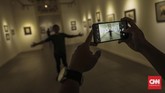 Pengunjung menikmati karya sketsa yang dipamerkan dalam Festival Sketsa Indonesia bertajuk Sketsaforia Urban di Galeri Nasional, Jakarta, Jumat (13/9). (CNN Indonesia/Bisma Septalisma)