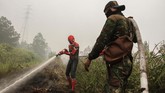 Seorang warga mengenakan kostum superhero membantu petugas BPBD Riau dan TNI Kodim 0313 Kampar saat memadamkan kebakaran lahan gambut di Rimbo Panjang, Kabupaten Kampar, Riau, 12 September 2019. (ANTARA FOTO/Rony Muharrman)