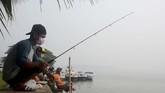 Sejumlah pemancing menggunakan masker saat memancing di tengah kabut di Tepian Kayan, Tanjung Selor, Kaltara, Minggu (15/09). Kabut asap dari kebakaran hutan membawa partikel-partikel halus, sehingga tak bisa dihalau menggunakan masker biasa, tapi setidaknya masker N-95. (ANTARA FOTO/Iskandar Zulkarnen)
