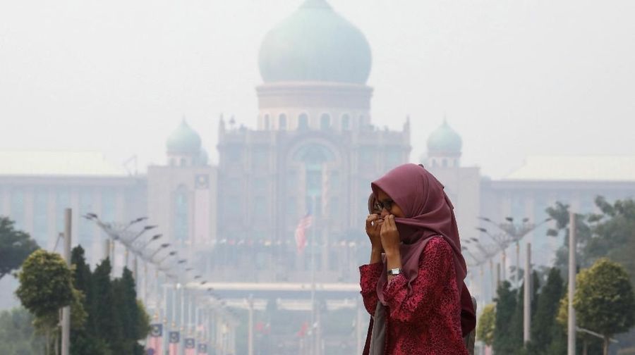 A woman covers her face with a scarf in front of the Malaysia's Prime Minister's office, which is shrouded in haze, in Putrajaya, Malaysia, September 17, 2019. REUTERS/Lim Huey Teng