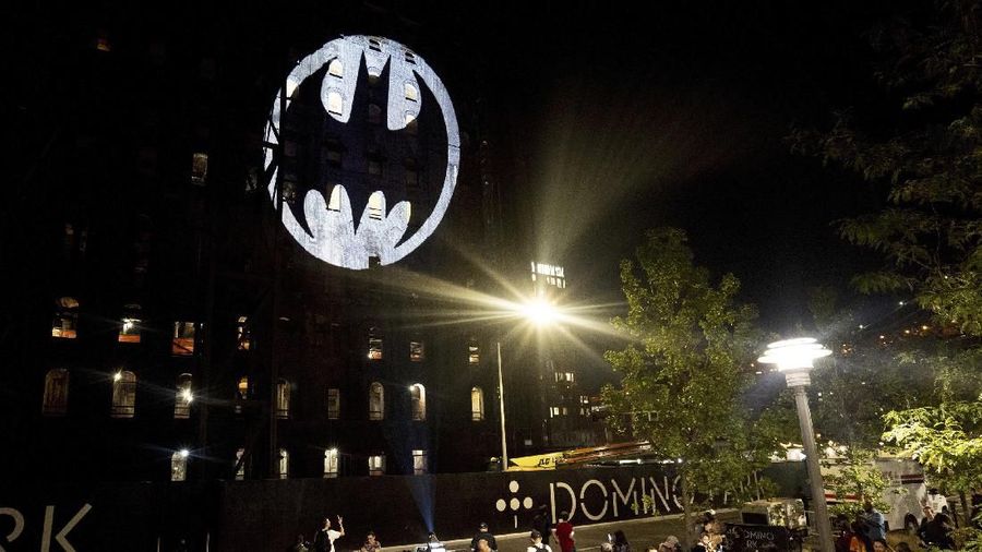 A man holds Batman balloons before a Bat-signal lighting during the commemorating of Batman's 80th anniversary in Mexico City, Saturday, Sept. 21, 2019. (AP Photo/Ginnette Riquelme)