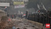 Mahasiswa membakar pembatas jalan saat kericuhan di depan gedung DPR. Aparat kemudian memadamkan api dan menembakan gas air mata ke arah mahasiswa. (CNN Indonesia/Bisma Septalisma).