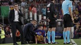 Lionel Messi mendapat perawatan tim medis di saat pelatih Barcelona Ernesto Valverde (kiri) mengamati pertandingan melawan Villarreal. (AP Photo/Joan Monfort)