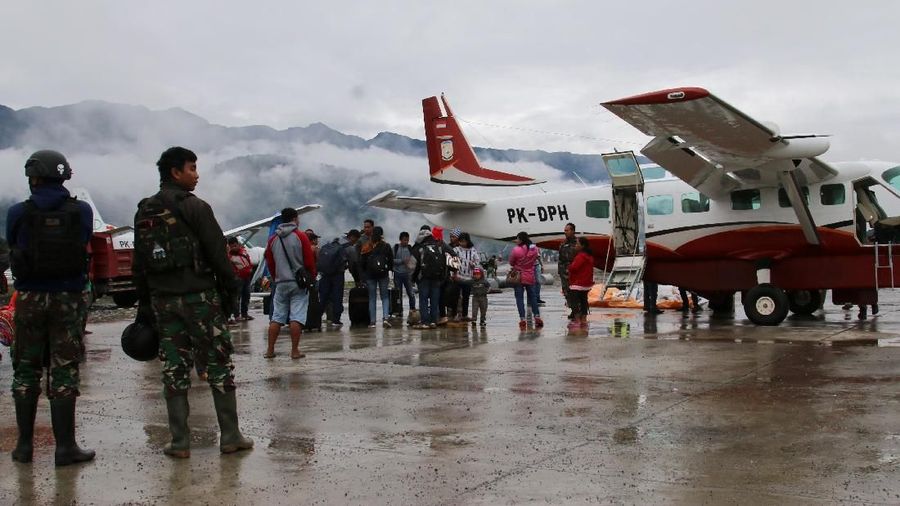Security officers stand guard as passengers wait to board an aircraft at Ilaga Airport in Puncak regency, Papua, Indonesia, October 2, 2019. Picture taken October 2, 2019  in this photo taken by Antara Foto.  Antara Foto/Sevianto Pakiding/via REUTERS   ATTENTION EDITORS - THIS IMAGE WAS PROVIDED BY A THIRD PARTY. MANDATORY CREDIT. INDONESIA OUT.