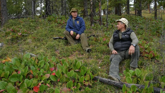 Presiden Rusia, Vladimir Putin (kiri) sedang duduk bersama Menteri Pertahanan Rusia, Sergei Shoigu, saat menjelajah hutan di Siberia. Keduanya mengambil cuti untuk bertualang menjelang ulang tahun Putin. (Alexei Druzhinin, Sputnik, Kremlin Pool Photo via AP)