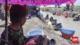 Seorang anak beristirahat makan di bawah naungan payung di sela-sela pencarian harta karun Sriwijaya bersama orang tuanya. (CNN Indonesia/Hafidz Trijatnika)