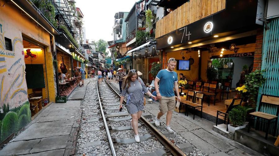 A woman sits on a railway track as tourists gather along it on a street in the Old Quarter of Hanoi, Vietnam October 8, 2019. Picture taken October 8, 2019. REUTERS/Kham