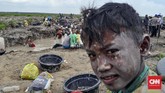 Seorang anak yang rela bolos demi ikut orang tuanya mencari harta karun Sriwijaya dengan wajah berlumuran kotoran dari lumpur dasar kanal, Desa Pelimbangan, Kecamatan Cengal, Kabupaten OKI, Sumsel. (CNN Indonesia/Hafidz Trijatnika)