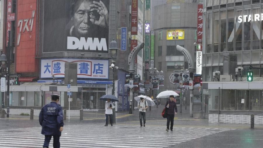 Few people walk in crossing in Shibuya district, Tokyo Saturday, Oct. 12, 2019. Tokyo and surrounding areas braced for a powerful typhoon forecast as the worst in six decades, with streets and trains stations unusually quiet Saturday as rain poured over the city. (AP Photo/Kiichiro Sato)