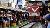 Namun padatnya aktivitas turisme di Train Street membuat jadwal kereta yang lewat terganggu, karena harus menahan laju agar tak membahayakan orang yang ada di sekitarnya. (AFP/Manan Vatsyayana)