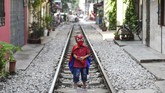 Anak kecil dengan kostum Spiderman berpose di tengah rel kereta Train Street, Hanoi, Vietnam. (AFP/Nhac Nguyen)
