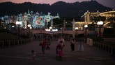 Para pengunjung berjalan pada dini hari di Disneyland Hong Kong. Selama beberapa bulan terakhir Hong Kong terus diterpa gelombang aksi demonstrasi sehingga sektor pariwisata pun terpengaruh. (AP Photo/Felipe Dana)