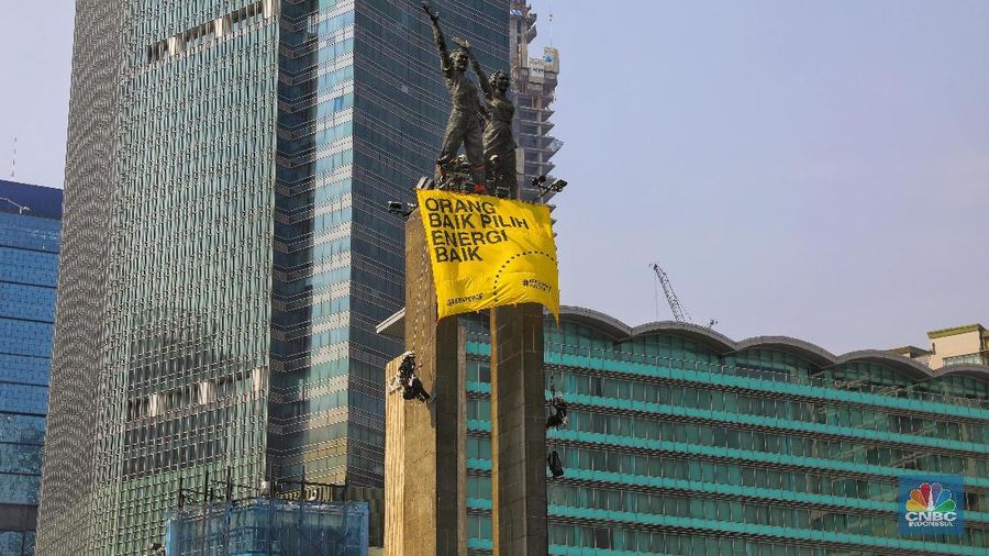 Greenpeace menyuarakan tuntutan mereka pada pemerintah dengan mengibarkan spanduk di patung ikonik Jakarta.