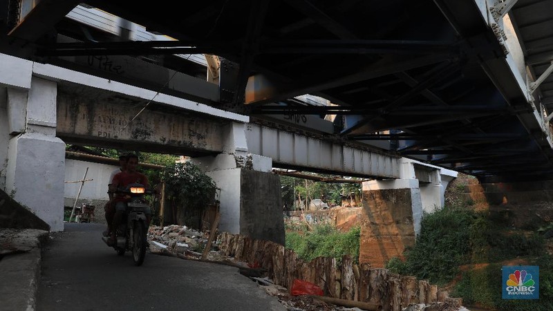 Sebagian jalan sudah tergerus oleh air kali dan hanya di tahan oleh beberapa kayu atau balok di sekitar.