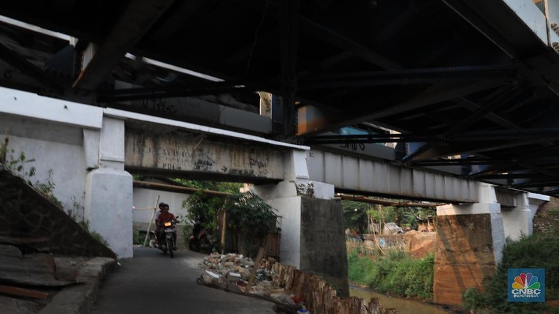 Sebagian jalan sudah tergerus oleh air kali dan hanya di tahan oleh beberapa kayu atau balok di sekitar.
