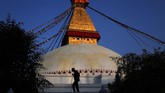 Seorang sesepuh Nepal berjalan melewati stupa Boudhanath di Kathmandu, Nepal. Stupa tua ini merupakan salah satu yang terbesar di dunia dan juga tempat berziarah penting bagi pemeluk agama Buddha, serta situs kebudayaan UNESCO. (AP Photo/Niranjan Shrestha)