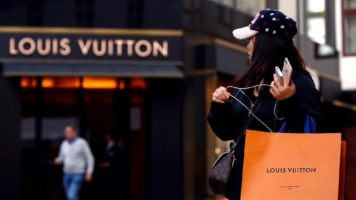 ILE PHOTO: A woman with a Louis Vuitton-branded shopping bag looks towards the entrance of a branch store by LVMH Moet Hennessy Louis Vuitton in Vienna, Austria October 4, 2018. REUTERS/Lisi Niesner