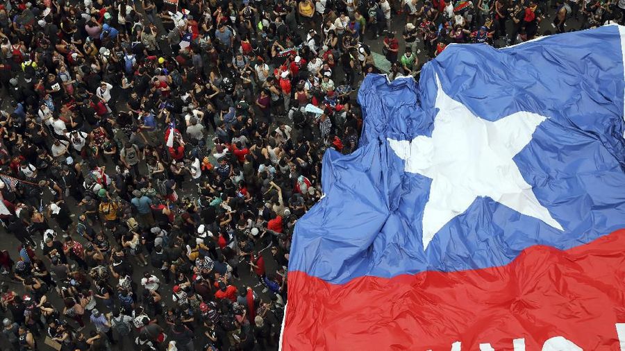 People gather during an anti-government protest in Santiago, Chile, Friday, Oct. 25, 2019. At least 19 people have died in the turmoil that has swept the South American nation. The unrest began as a protest over a 4-cent increase in subway fares and soon morphed into a larger movement over growing inequality in one of Latin America's wealthiest countries. (AP Photo/Rodrigo Abd)