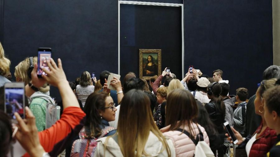 Tourists wait to see Leonardo da Vinci's painting Mona Lisa, at the Louvre museum, in Paris, Wednesday, Oct. 23, 2019. The Louvre, the home of the "Mona Lisa," is commemorating the 500th anniversary of Leonardo Da Vinci's death with a landmark new exhibit. (AP Photo/Thibault Camus)